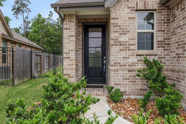 entrance to property featuring fence and brick siding