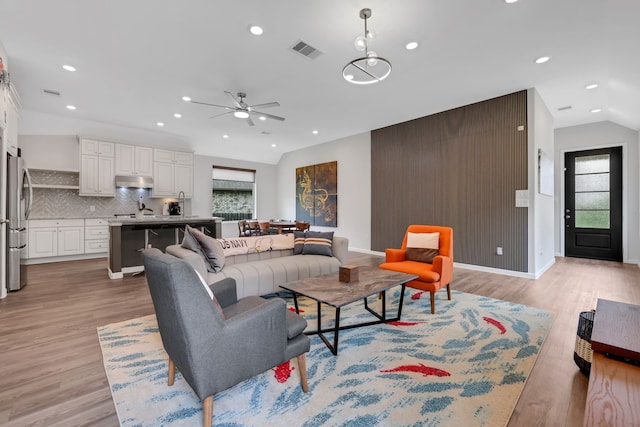 living area featuring ceiling fan, recessed lighting, lofted ceiling, light wood-type flooring, and visible vents