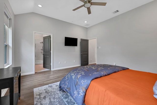 bedroom with connected bathroom, baseboards, wood finished floors, vaulted ceiling, and visible vents