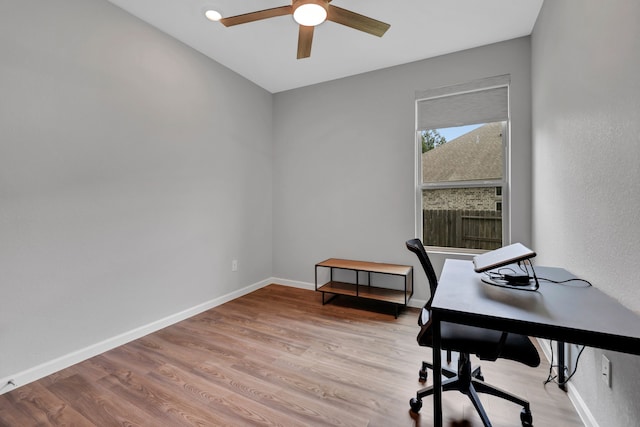 office area with a ceiling fan, baseboards, and light wood-type flooring
