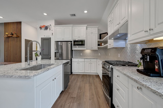 kitchen with under cabinet range hood, white cabinetry, appliances with stainless steel finishes, and a sink