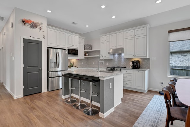 kitchen with decorative backsplash, built in microwave, a sink, stainless steel fridge with ice dispenser, and under cabinet range hood