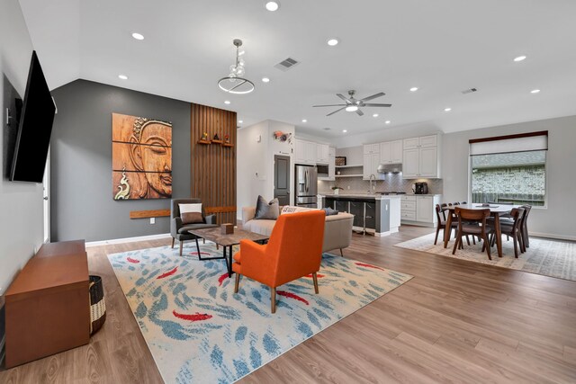 living area with ceiling fan, visible vents, lofted ceiling, recessed lighting, and light wood-style flooring