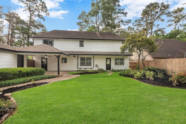 rear view of house with a lawn, a ceiling fan, fence, a patio, and roof with shingles
