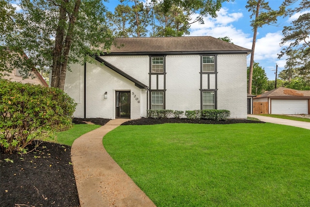 view of front of home with brick siding, a shingled roof, a front lawn, and an outdoor structure