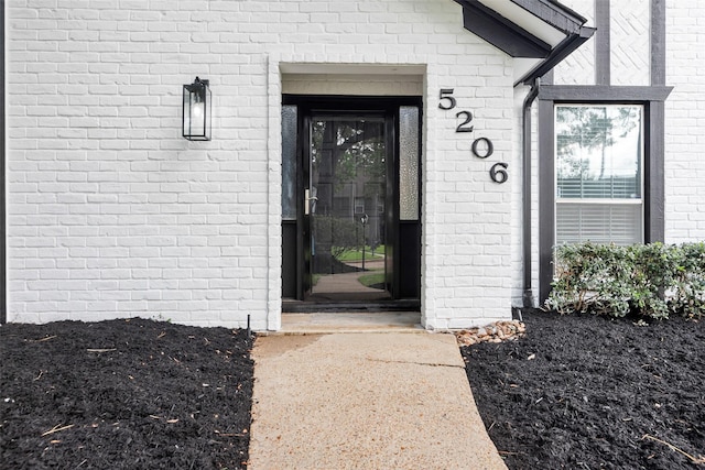 view of exterior entry featuring brick siding
