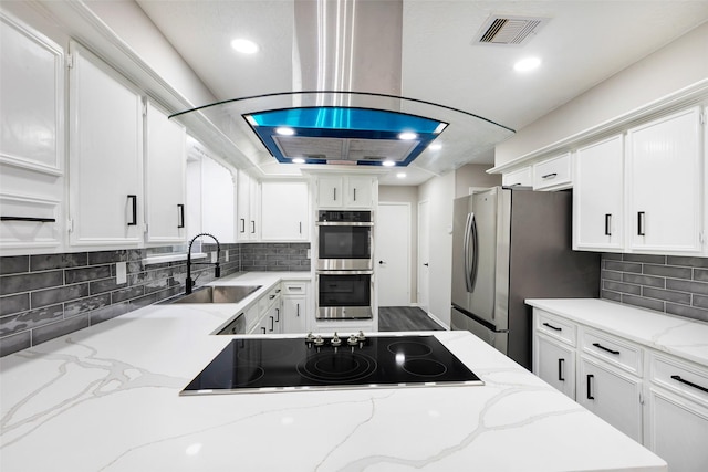 kitchen featuring stainless steel appliances, a sink, visible vents, backsplash, and white cabinetry