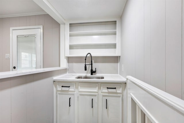 bar with a decorative wall, ornamental molding, and a sink