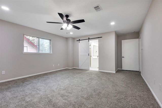 unfurnished bedroom featuring a barn door, baseboards, and carpet flooring