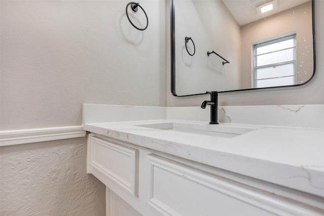 bathroom with a textured wall and vanity