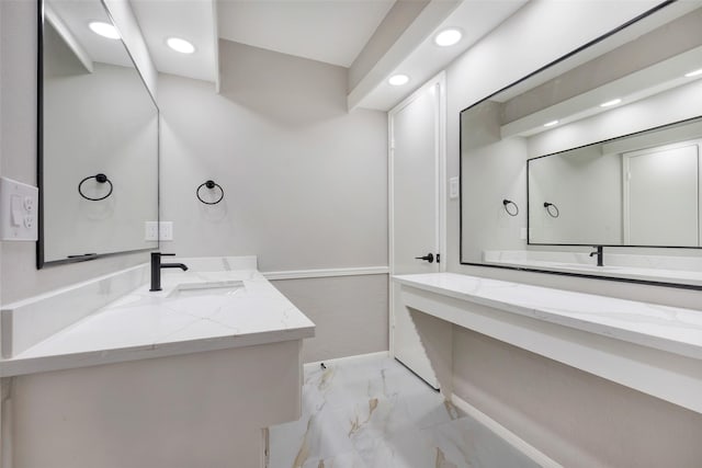 full bath featuring two vanities, marble finish floor, a sink, and recessed lighting