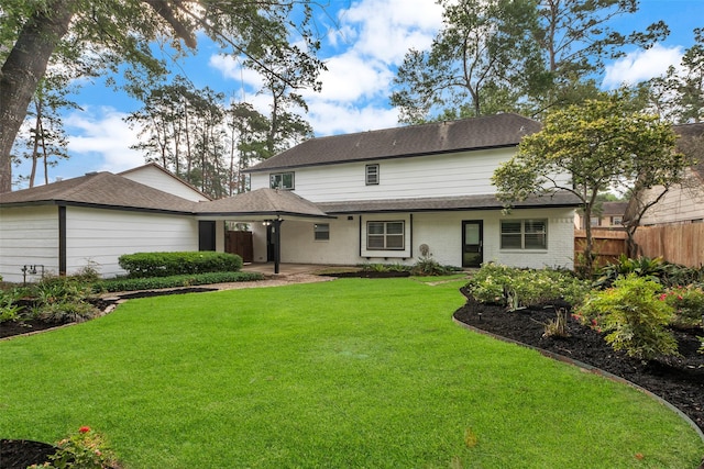 rear view of property featuring a patio area, roof with shingles, fence, and a yard