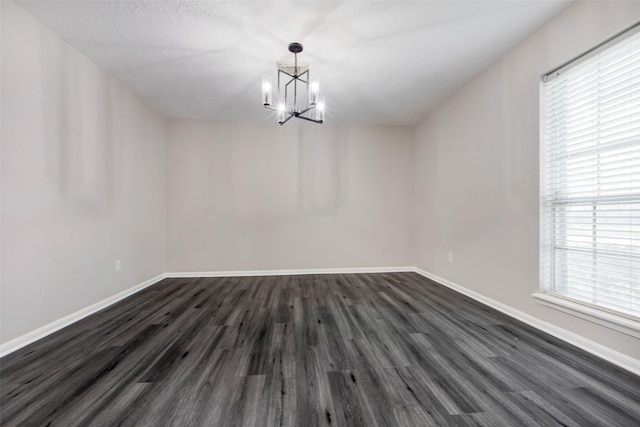 unfurnished dining area with baseboards, dark wood-style floors, a notable chandelier, and a healthy amount of sunlight