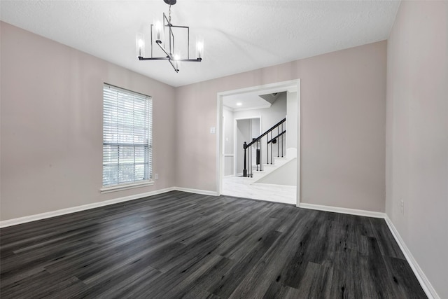 unfurnished dining area featuring dark wood-style floors, a textured ceiling, baseboards, a notable chandelier, and stairs