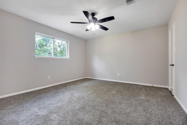 carpeted spare room featuring baseboards, visible vents, and ceiling fan
