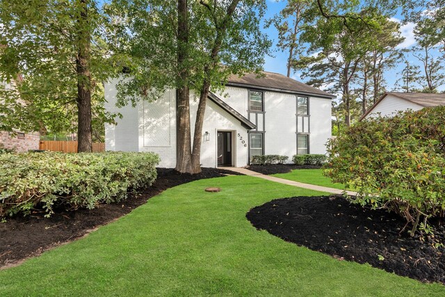 view of front facade with a front lawn, brick siding, and fence