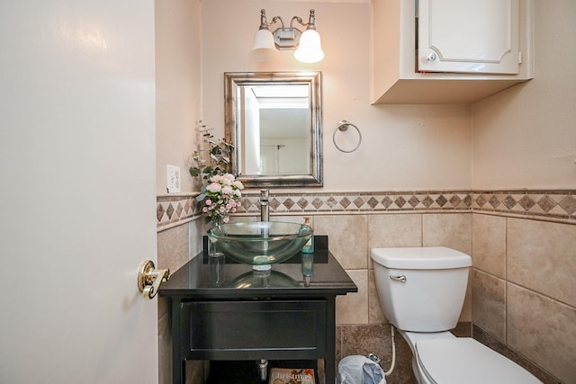 bathroom featuring vanity, toilet, a wainscoted wall, and tile walls