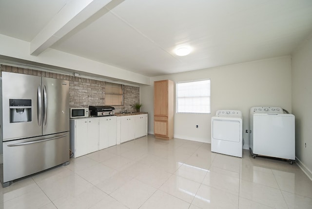 kitchen with light tile patterned floors, stainless steel fridge, washer and dryer, white microwave, and backsplash