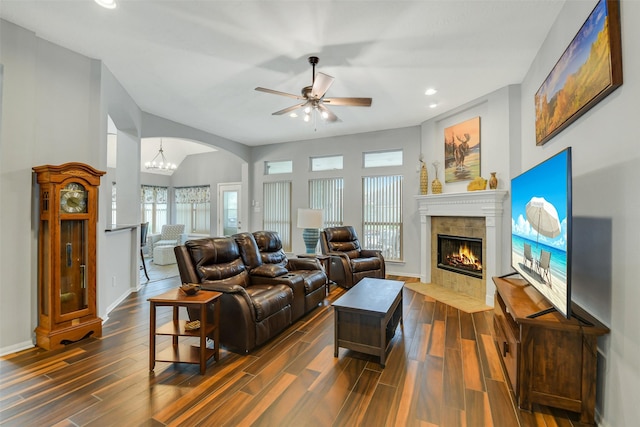 living area with recessed lighting, dark wood-style floors, a ceiling fan, arched walkways, and a tiled fireplace