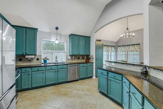 kitchen featuring arched walkways, a sink, lofted ceiling, decorative backsplash, and appliances with stainless steel finishes