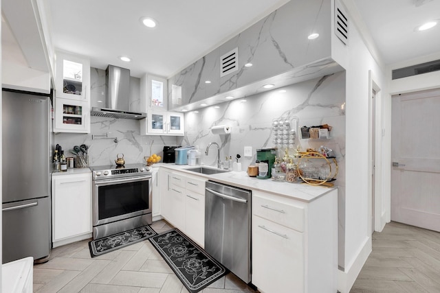kitchen featuring tasteful backsplash, a sink, stainless steel appliances, white cabinets, and wall chimney exhaust hood
