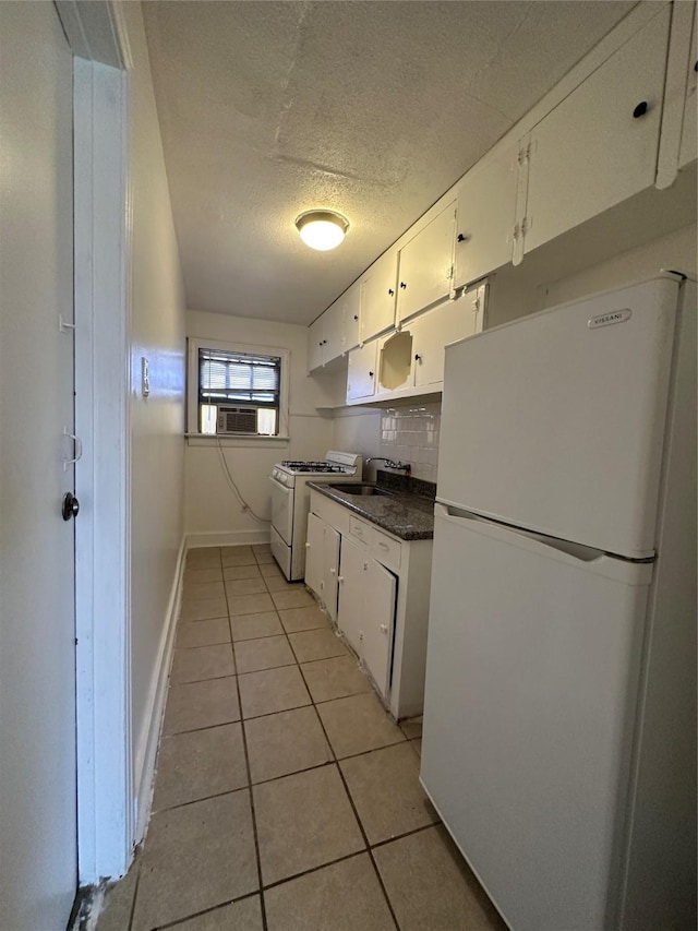 2711 Ruth St, Houston, TX 77004 - kitchen with white cabinets, dark countertops, light tile patterned flooring, and white appliances