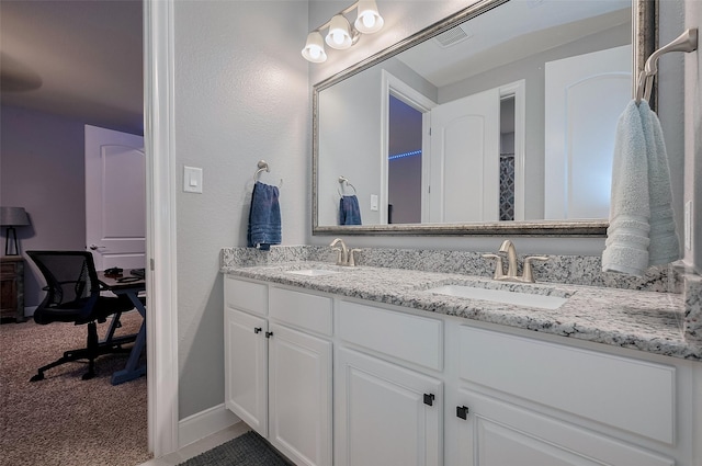 full bath featuring double vanity, a sink, baseboards, and visible vents