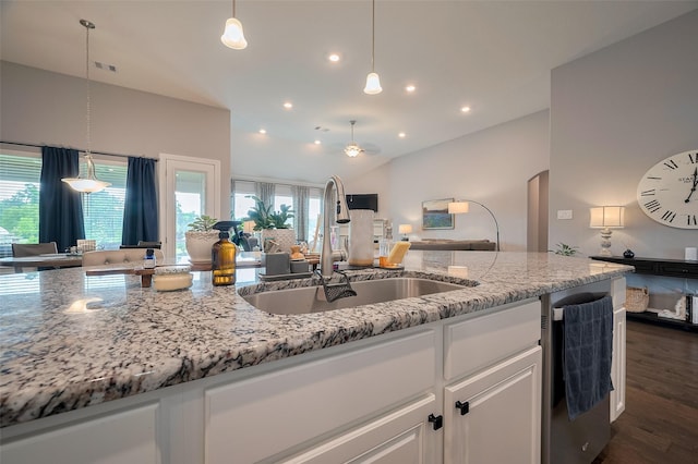 kitchen featuring a sink, light stone counters, white cabinets, open floor plan, and recessed lighting