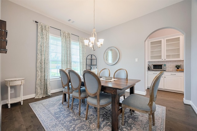 dining area featuring baseboards, an inviting chandelier, dark wood finished floors, and a toaster
