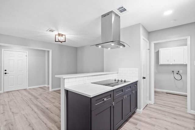 13400 Nicholson Rd, Conroe, TX 77303 - kitchen with island exhaust hood, light countertops, light wood finished floors, black electric stovetop, and a peninsula