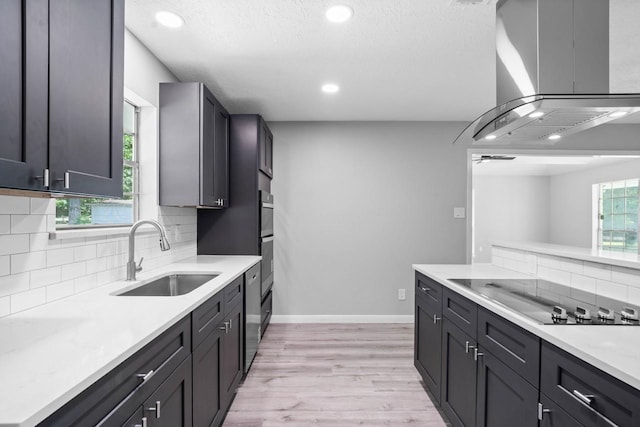 13400 Nicholson Rd, Conroe, TX 77303 - kitchen with black electric stovetop, island exhaust hood, decorative backsplash, light countertops, and light wood-type flooring