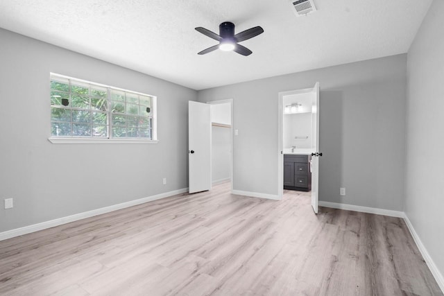13400 Nicholson Rd, Conroe, TX 77303 - unfurnished bedroom featuring light wood-type flooring, connected bathroom, ceiling fan, and a textured ceiling