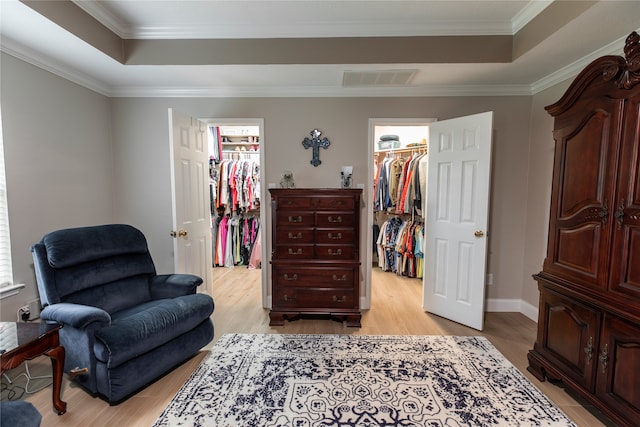 sitting room featuring crown molding, a tray ceiling, visible vents, and light wood finished floors
