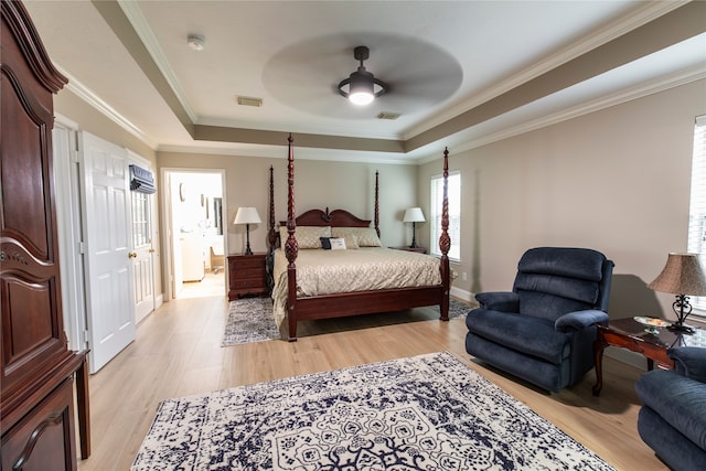 bedroom featuring visible vents, crown molding, baseboards, a tray ceiling, and light wood finished floors