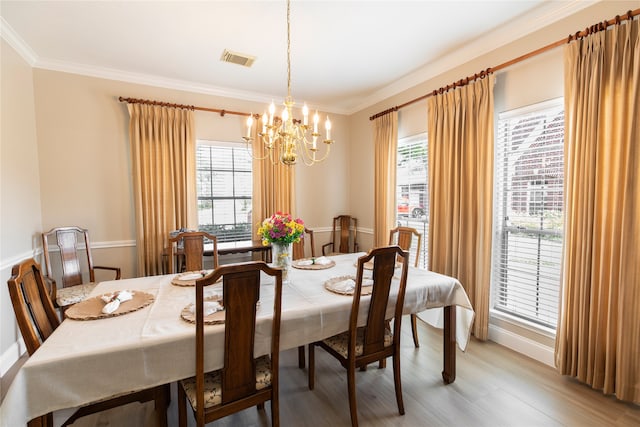 dining area featuring visible vents, a healthy amount of sunlight, an inviting chandelier, and light wood-style flooring