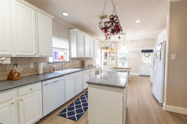 kitchen featuring a kitchen island, white appliances, white cabinetry, tasteful backsplash, and a sink