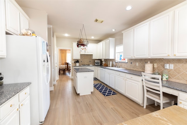 kitchen featuring visible vents, a sink, white cabinets, and white appliances
