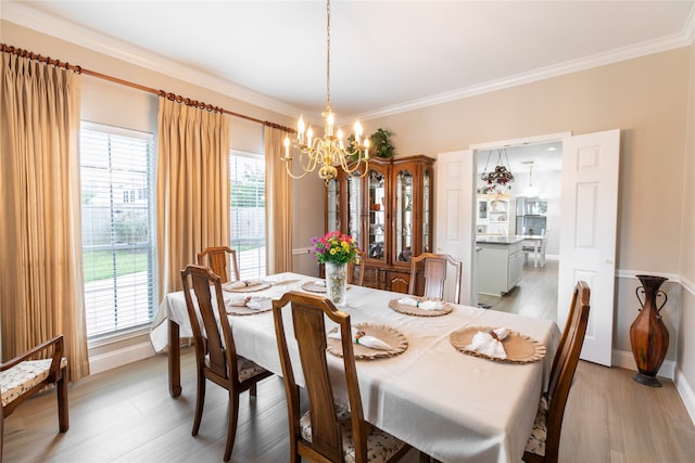 dining space featuring light wood-style floors, baseboards, ornamental molding, and a chandelier