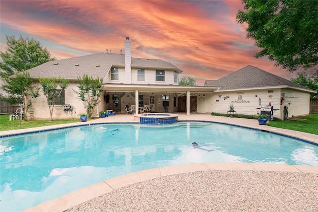 pool at dusk featuring a patio area, fence, and a pool with connected hot tub