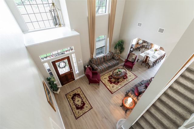 living room with visible vents, stairs, a high ceiling, and wood finished floors