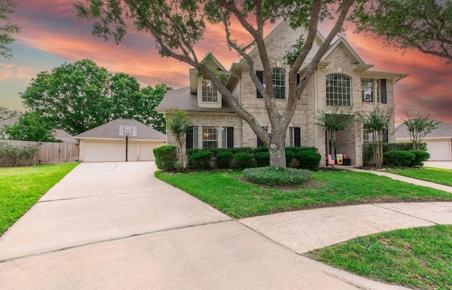 french provincial home with a detached garage, a yard, and fence