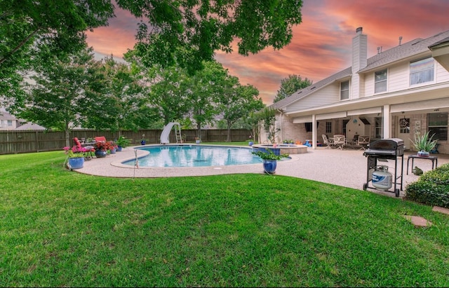 view of swimming pool with a fenced backyard, a yard, a patio, a water slide, and a grill