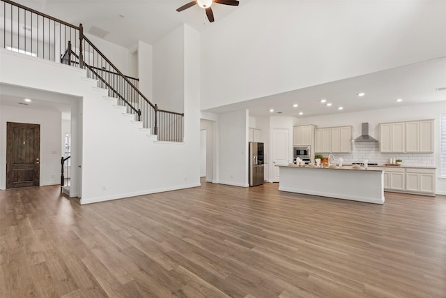 40805 Iver Ln, Magnolia, TX 77354 - unfurnished living room with high vaulted ceiling, a ceiling fan, stairway, and light wood-style flooring