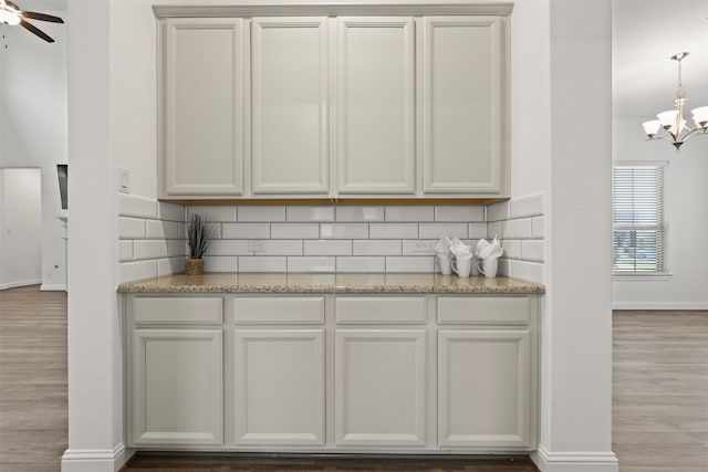 40805 Iver Ln, Magnolia, TX 77354 - bar with tasteful backsplash, wood finished floors, decorative light fixtures, ceiling fan with notable chandelier, and baseboards