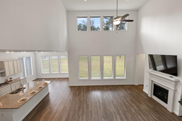 40805 Iver Ln, Magnolia, TX 77354 - unfurnished living room with ceiling fan, a sink, a fireplace, and a towering ceiling