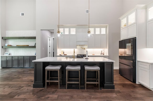 kitchen featuring a high ceiling, black refrigerator, and tasteful backsplash