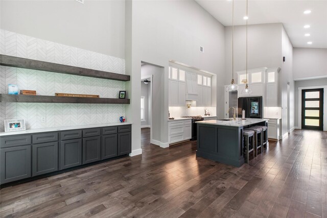 kitchen with decorative backsplash, stainless steel stove, a towering ceiling, and light countertops