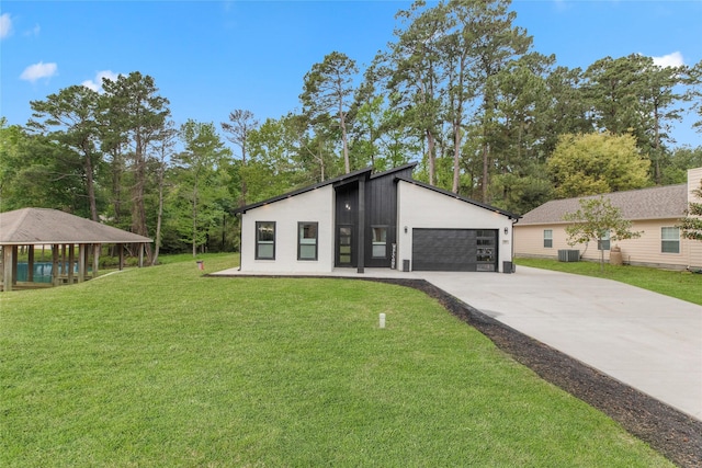 mid-century inspired home featuring a garage, central air condition unit, and a front lawn