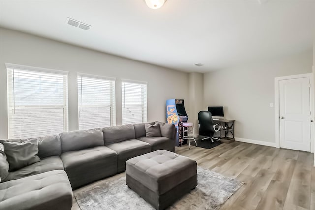 living room with visible vents, light wood-style flooring, and baseboards