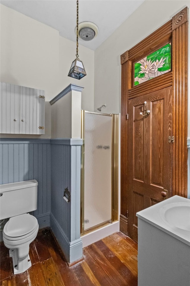 1003 Sealy St, Galveston, TX 77550 - bathroom featuring wood finished floors, a stall shower, a sink, a wainscoted wall, and toilet